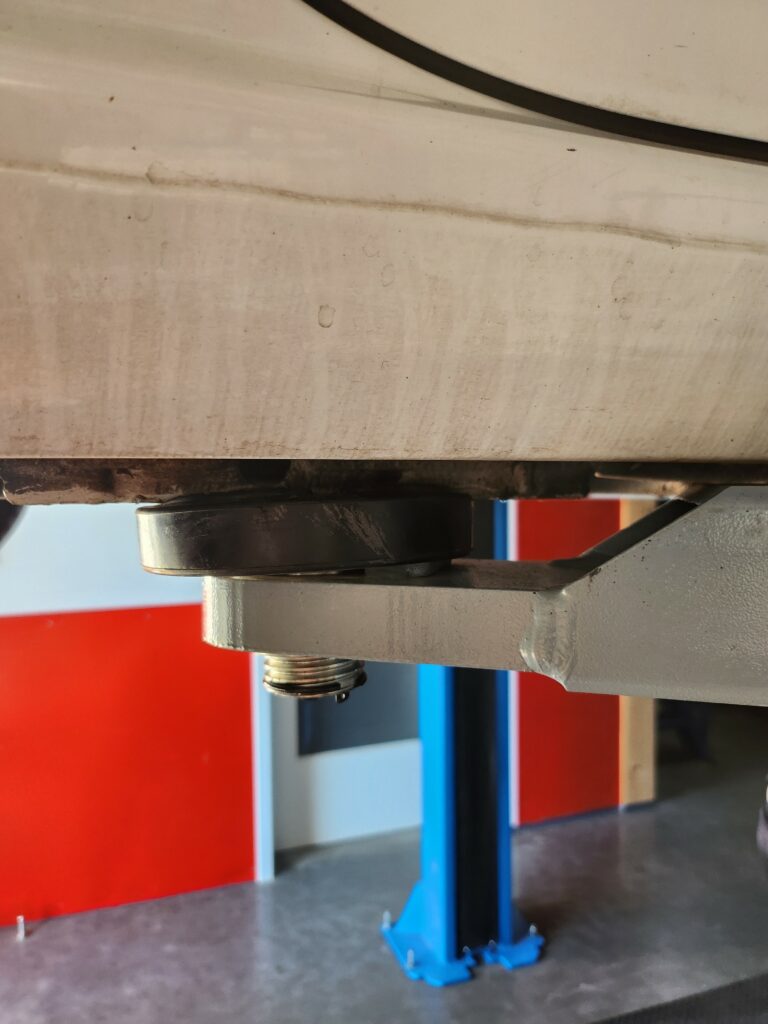 Tragarme mit Drehteller einer Hebebühne an den Ansatzpunkten eines Fahrzeugs ausgerichtet Tragarme mit Drehteller einer Hebebühne an den Ansatzpunkten eines Fahrzeugs ausgerichtet